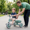 Toddler riding a green convertible trike with a carbon steel frame and detachable storage basket for safe outdoor fun.