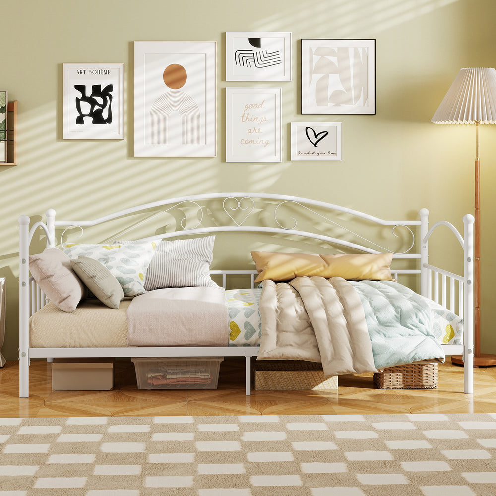 Twin size white metal daybed frame with heart-shaped decoration, featuring cozy bedding and ample under-bed storage.