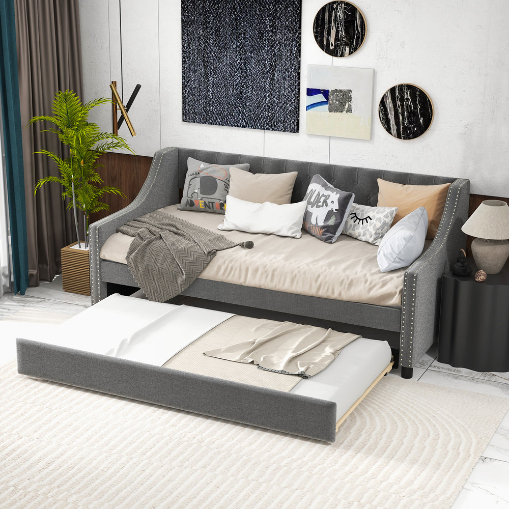 Twin size gray daybed with trundle, featuring curved armrests and soft upholstery, ideal for space-saving sleeping.