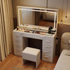 Vanity desk with mirror and lights in white features 10 drawers, a cushioned stool, and charging station for makeup.