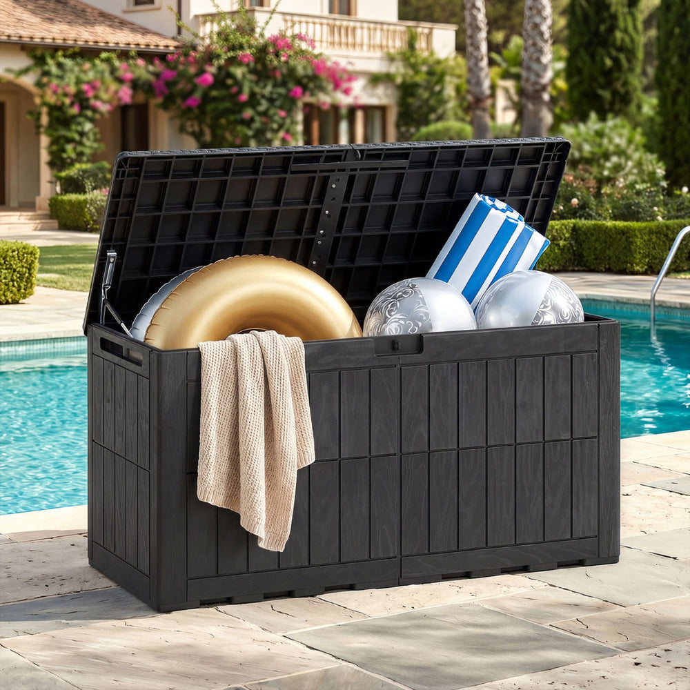 Black waterproof lockable outdoor deck box with pool supplies, cushions, and a blanket, perfect for patio storage.