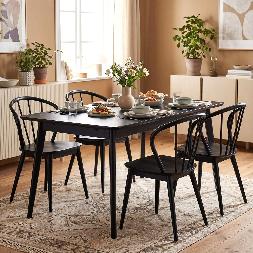 Set of four black Windsor dining chairs with spindle backrest, featuring rubber wood construction for stability and.