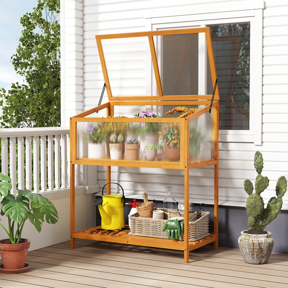 Wood cold frame greenhouse with transparent roof and slatted storage shelf for organizing gardening tools on a patio.