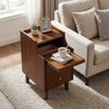 Brown wood nightstand with a drawer and solid wood legs, styled beside a sofa, perfect for bedroom storage.