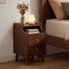 Wood nightstand in brown with two drawers and solid wood legs, perfect for bedroom storage beside a bed.