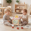Wooden activity cube with sensory toys, featuring shape matching blocks and a pretend kitchen, perfect for toddlers.