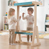 Children using a wooden art easel with a transparent board and paper roll, featuring a fir wood frame for stability.