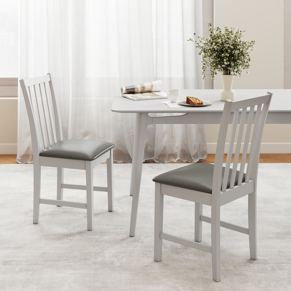 Two white wooden dining chairs with padded seats, crafted from rubber wood, ideal for dining rooms or cafes.