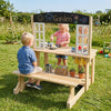 Wooden pretend play kitchen with bench, featuring stoves, sink, and accessories for imaginative outdoor play.