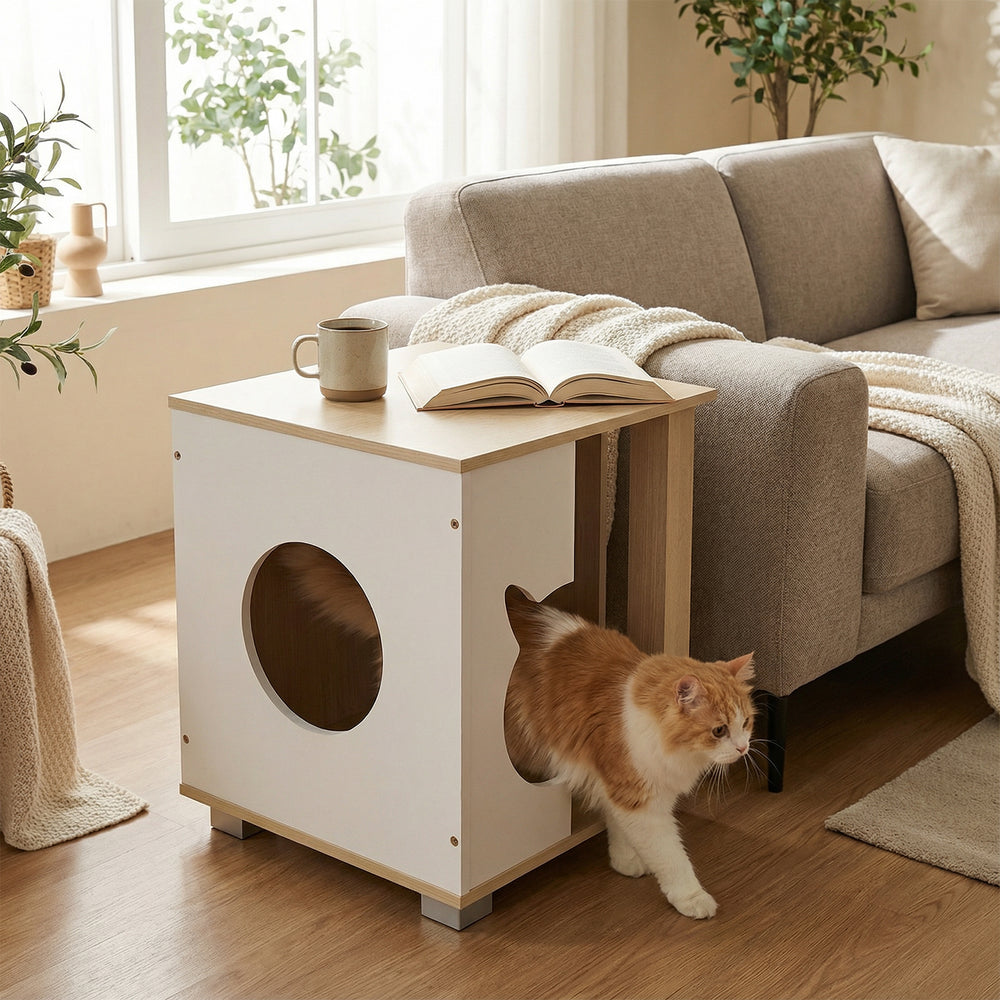 Wooden semi-enclosed cat condo with kitty head entry, natural finish, serving as a side table for decor and snacks.
