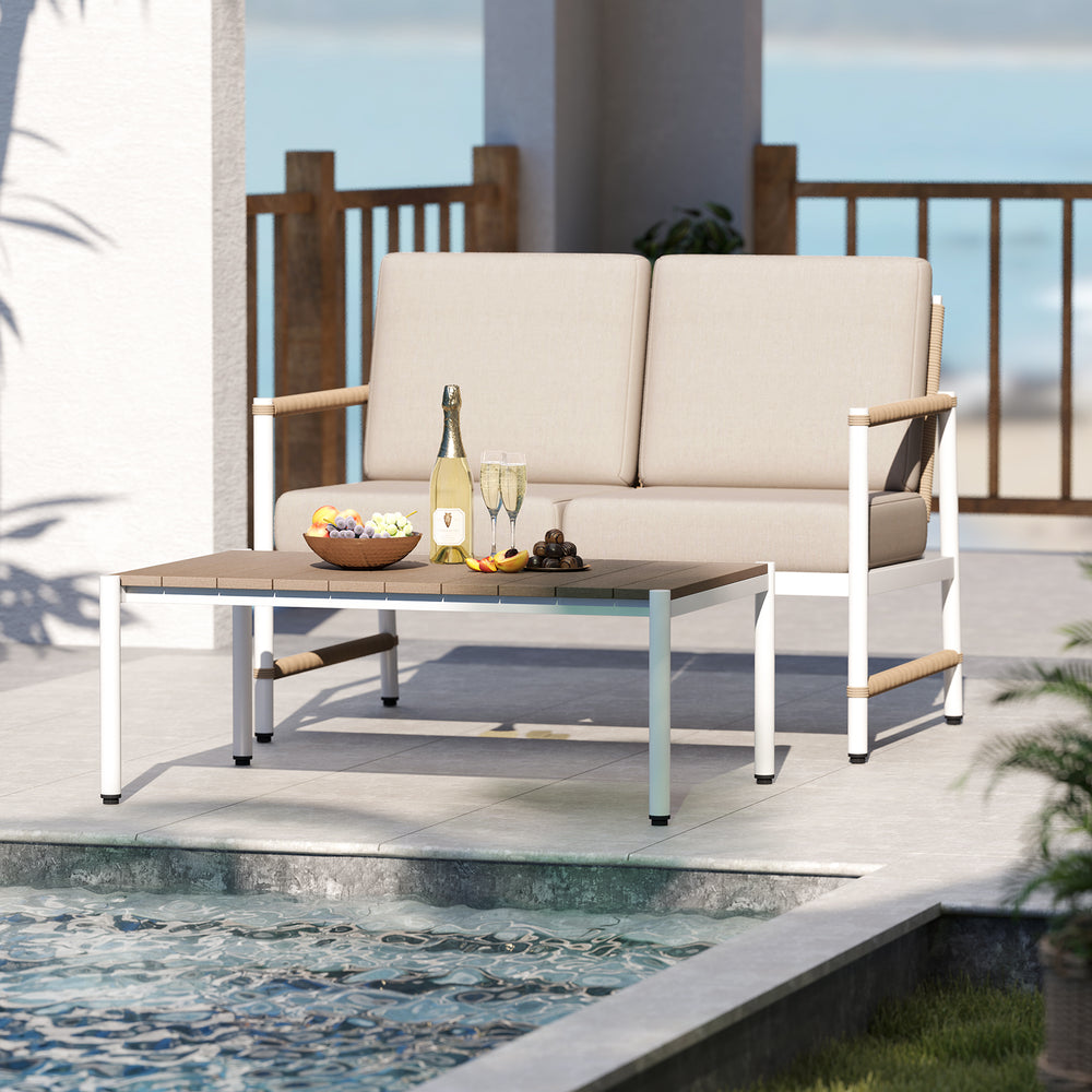 Cozy patio loveseat sofa with thick cushions and slatted PS tabletop, perfect for poolside relaxation.