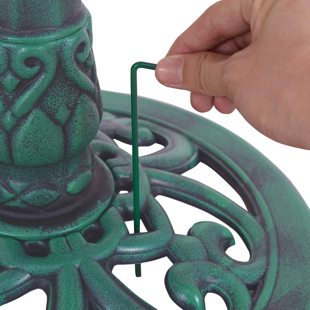 Close-up of the green pedestal bird bath feeder showing assembly with a hexagonal center and ground stake for stability.