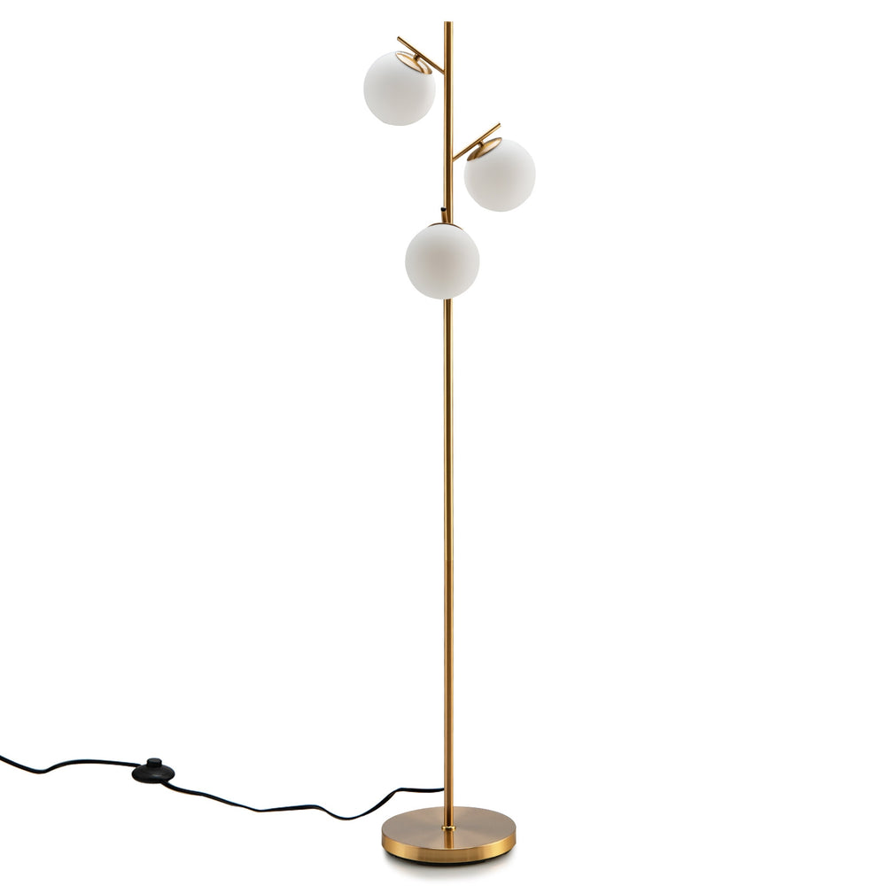 Three-globe floor lamp in gold with glass shades and foot switch, perfect for stylish corner lighting in any decor.