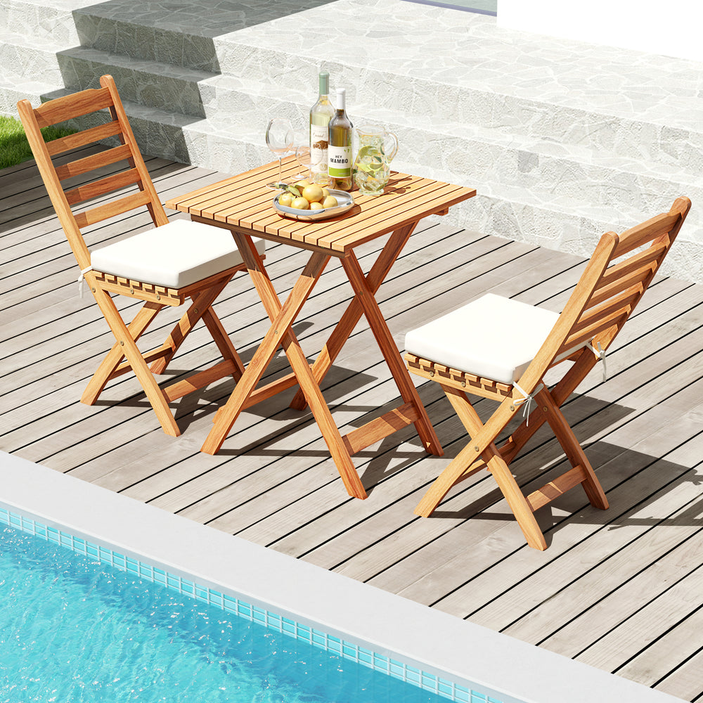 Folding chair table set with soft seat cushions in natural acacia wood, perfect for poolside relaxation.