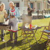 Folding picnic table featuring a rattan grain HDPE tabletop, set up for a backyard barbecue with food and drinks.