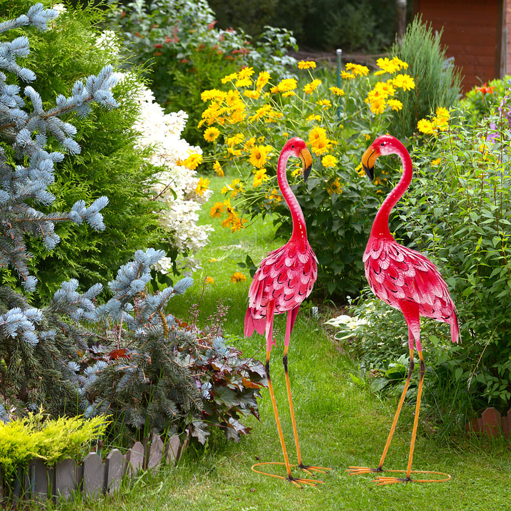 Two vibrant red flamingo garden statues with U-shaped stakes, adding charm to any backyard or garden setting.