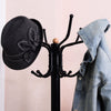 Vintage metal coat and hat tree stand with a black finish, featuring a hat and denim jacket hanging on its hooks.