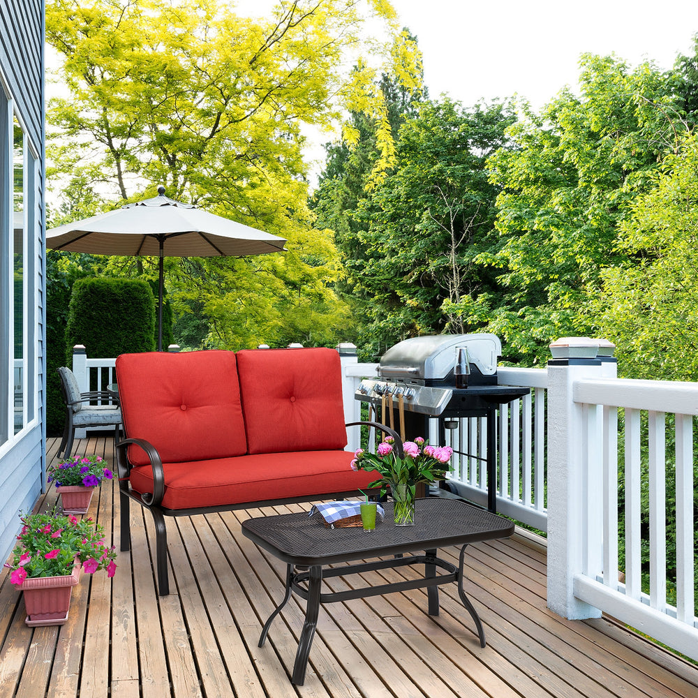 Red cushioned loveseat and coffee table set on a patio, perfect for outdoor relaxation and easy cleaning.