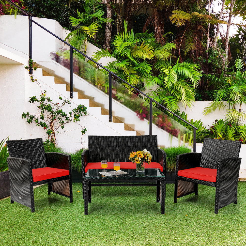 Four-piece patio rattan furniture set with red cushions, featuring a loveseat, two chairs, and a tempered glass coffee.