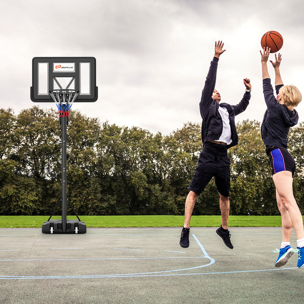 Two players engaging in a basketball game with a portable hoop featuring a shatterproof backboard and adjustable height.