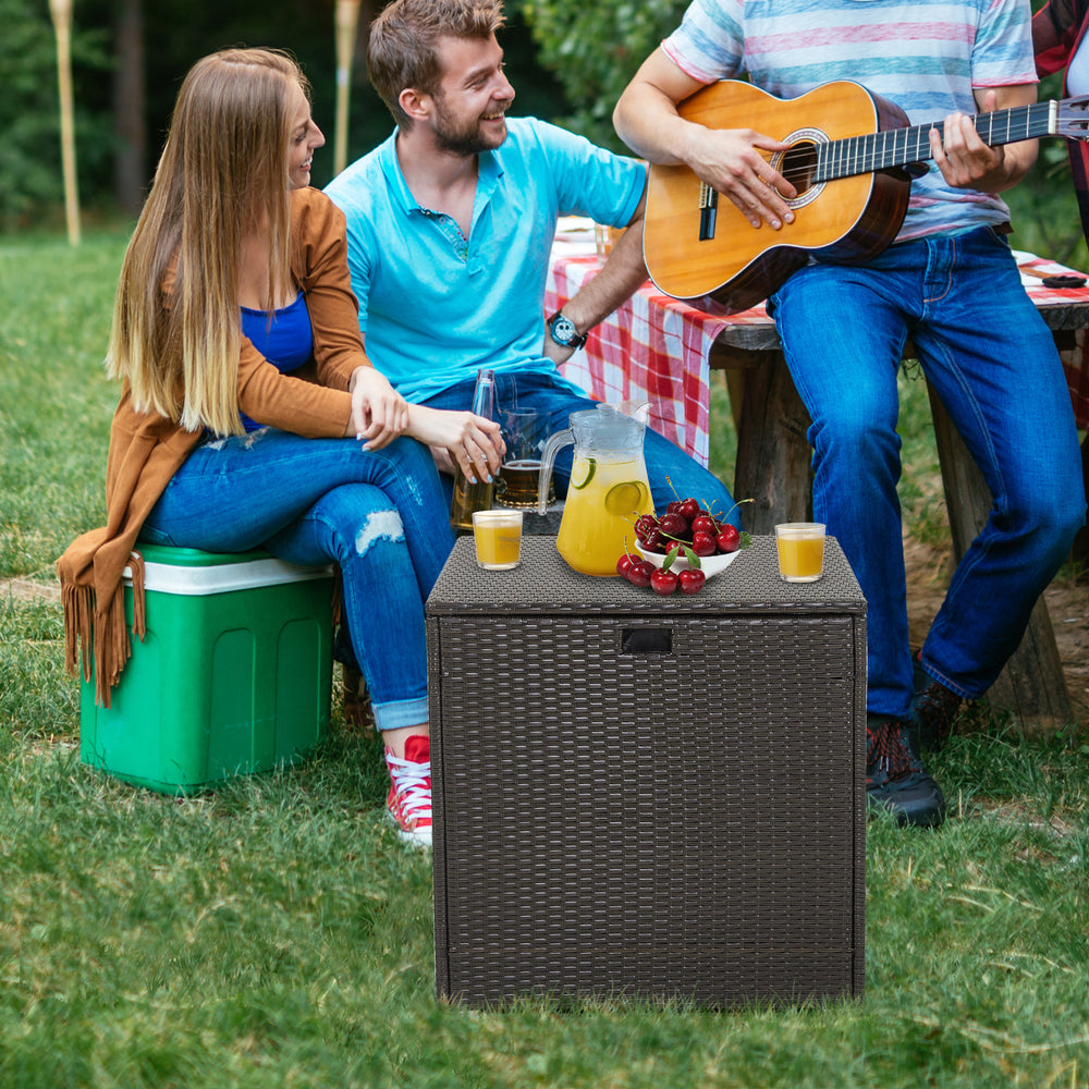 Rattan outdoor storage box with zippered liner, 72-gallon capacity, used as a coffee table for backyard gatherings.
