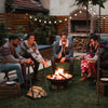 Triangle firewood rack in black with raised base, holding firewood for outdoor fireplace gatherings.