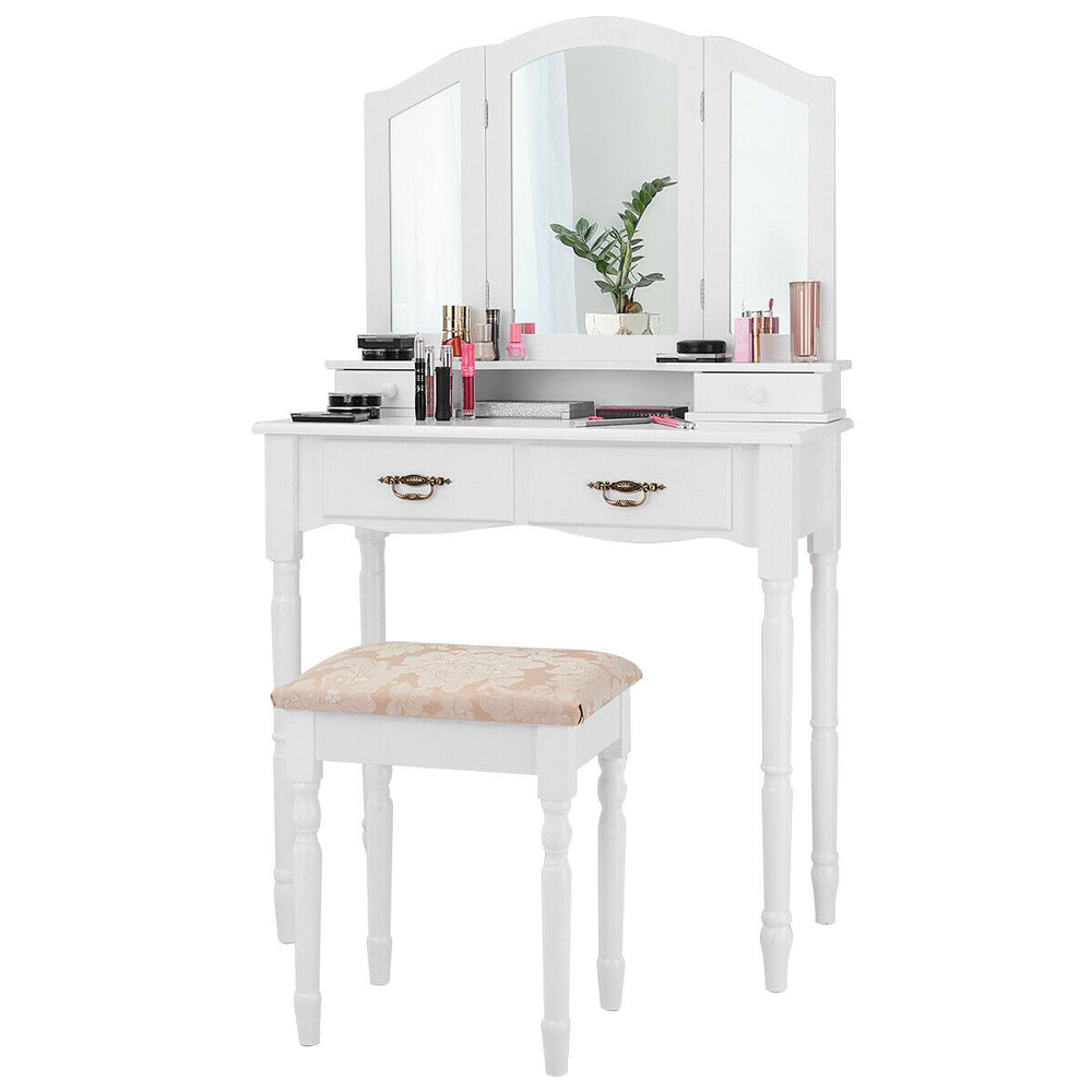 White vanity set with tri-fold mirror, cushioned stool, and four storage drawers for organizing cosmetics.