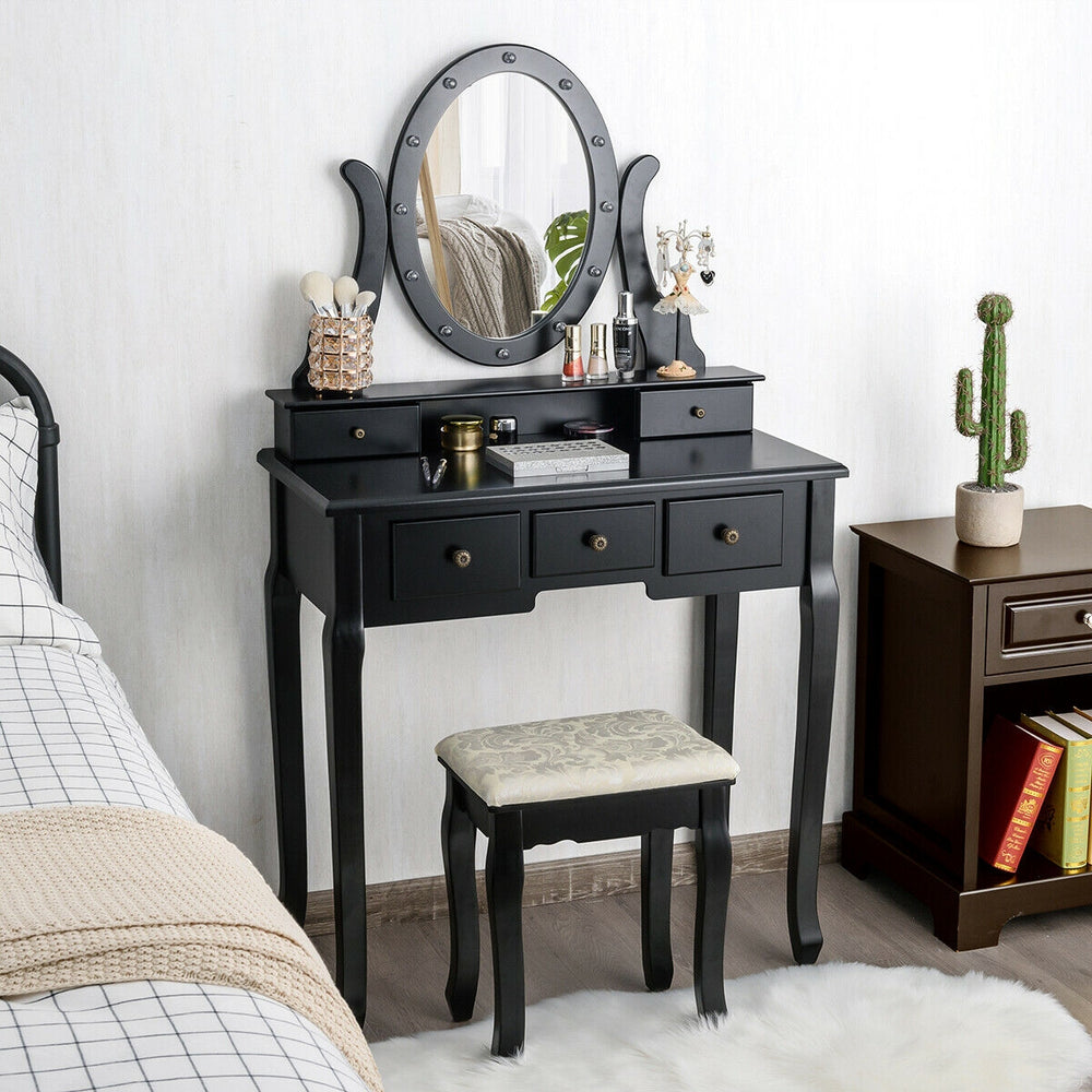 Black vanity table set with oval mirror and 12 LED bulbs, featuring 5 drawers and cushioned stool for versatile use.
