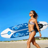 Woman walking on the beach with a 6 feet surfboard featuring a durable foam top and removable fins.