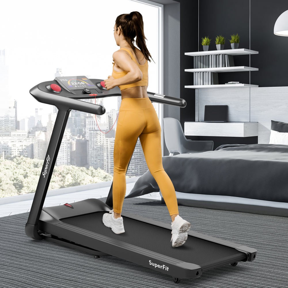 User running on the SuperFit 4.75HP folding treadmill with touch screen control in a modern bedroom setting.