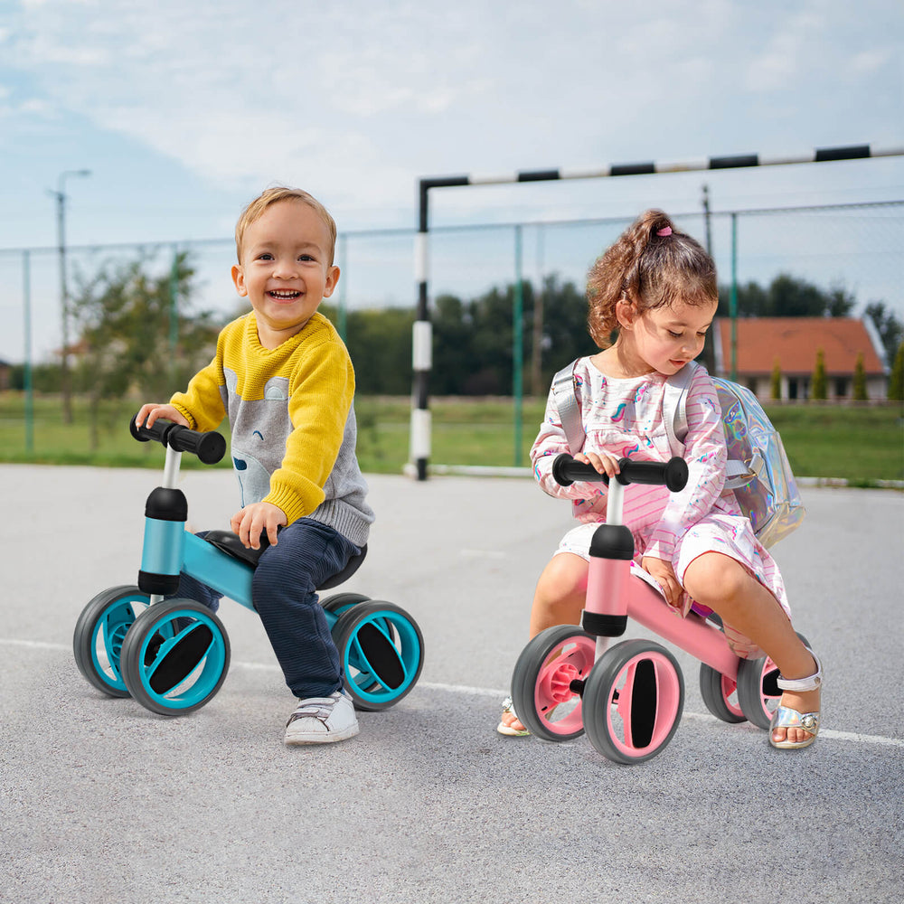 Two toddlers riding a 4-wheel baby balance bike in blue and pink, designed for stability and safety for ages 1-2.