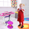 Child playing with a pink 37 key electronic keyboard toy piano, featuring a detachable microphone and stool for fun.