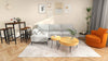 L-shaped modular sofa with steel backrest, 48-inch pub dining table, and nesting coffee tables in a modern living space.