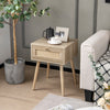 Modern rattan nightstand with drawer and solid wood legs, featuring a natural oak finish for bedroom or living room.