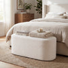 Upholstered oval ottoman bench in beige with corduroy surface, perfect for bedroom or living room use.