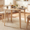Round rubber wood dining table set with four padded chairs, designed for comfort and space-saving in a cozy kitchen.