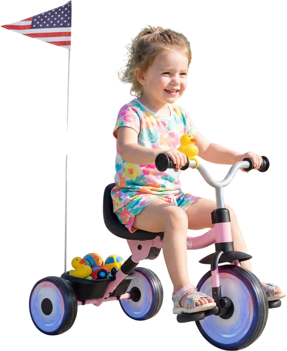 Toddler riding the Glowing Wheels Tricycle with a basket, duck bell, and glowing wheels in a park setting.