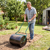 Man using a 12-gallon lawn roller in the garden, filled with water or sand for effective soil leveling.