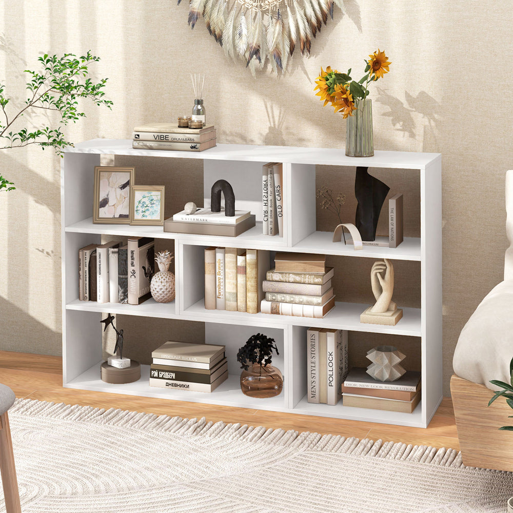 Concave and convex white bookshelf with three open shelves, perfect for displaying items in a living room or office.