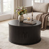 Round black coffee table with storage, featuring a fluted design and sliding tambour door for organized living room use.