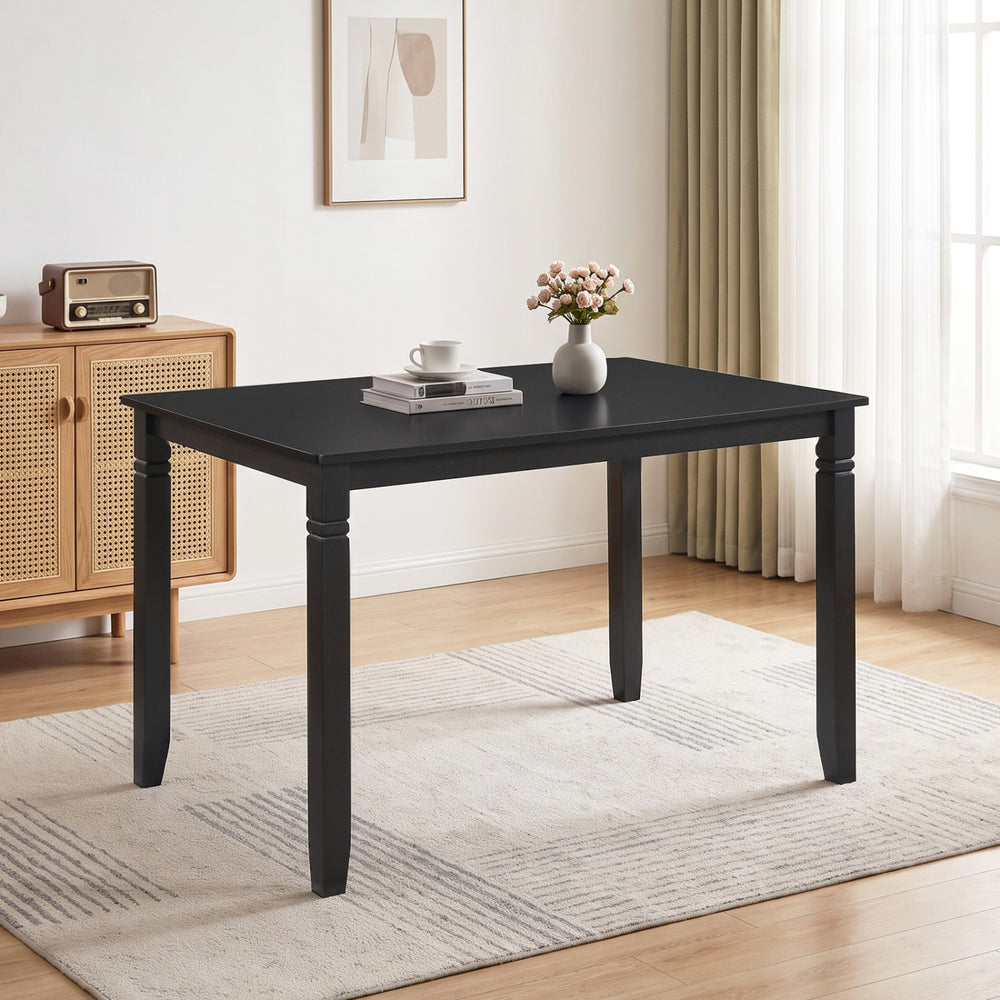 Rectangular black kitchen table with solid rubber wood legs, comfortably seating four, featuring elegant engraved leg detailing.