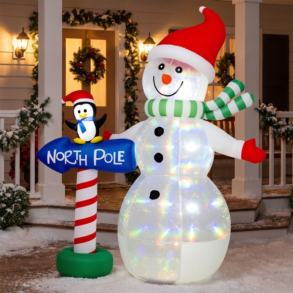 6 FT Christmas inflatable snowman with penguin and North Pole sign, glowing with colorful LED lights in a snowy porch scene.