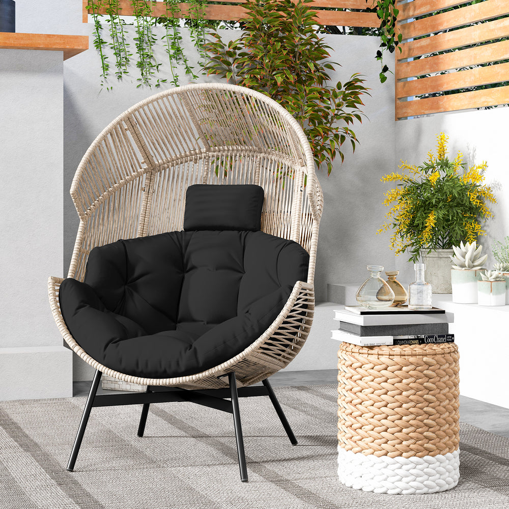 Wicker oversized egg style chair with black cushions and headrest, perfect for backyard or living room relaxation.