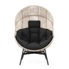 Oversized wicker egg chair with black cushions and headrest, featuring a light brown rattan design for stylish comfort.