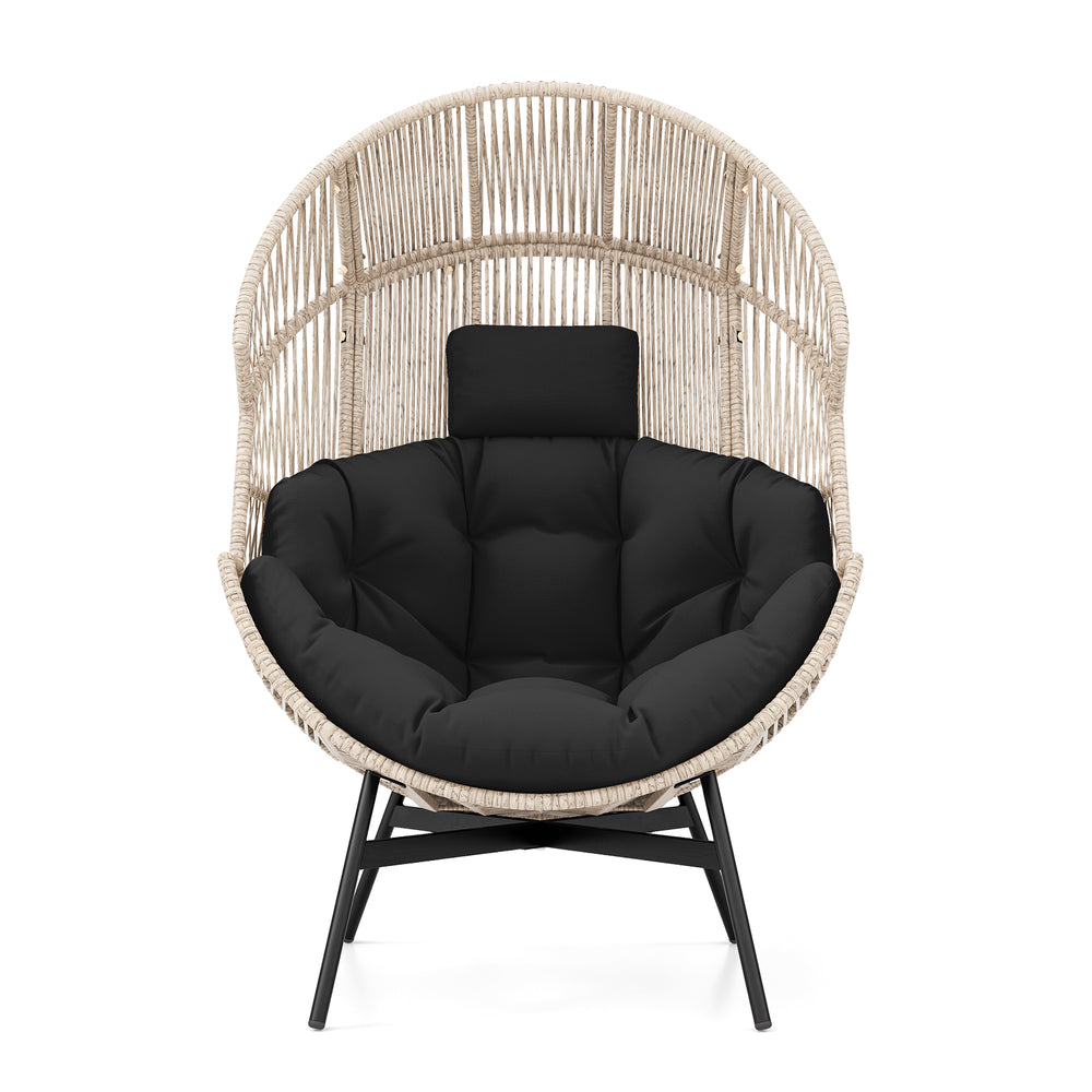 Oversized wicker egg chair with black cushions and headrest, featuring a light brown rattan design for stylish comfort.